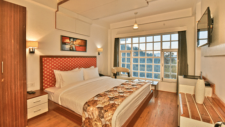 Bedroom with a wooden wardrobe next to it at DLS Hillcrest Resort, Shimla.